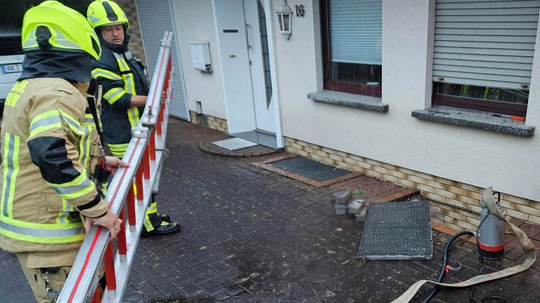 Die Mitglieder der Freiwilligen Feuerwehr aus Kirchen im Westerwald stellen Absperrgitter vor einem Haus auf