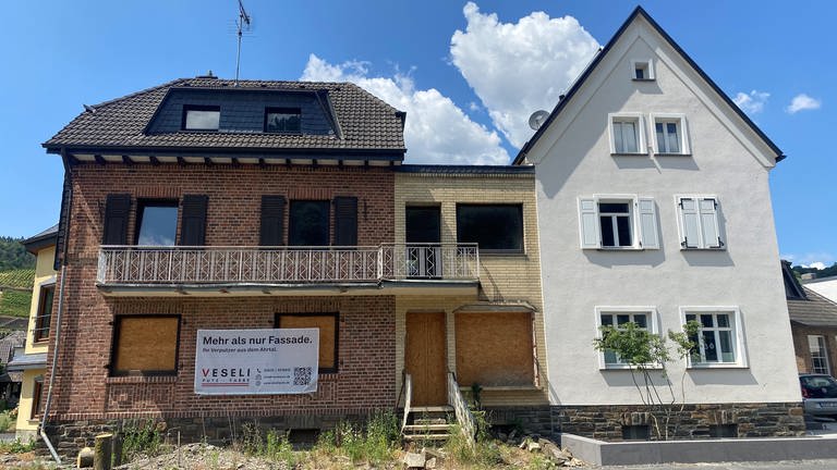 Von der Flutkatastrophe im Ahrtal betroffene Häuser in Dernau - zwei noch mit Brettern vernagelt, ein drittes bereits neu verputzt. (Foto: SWR)