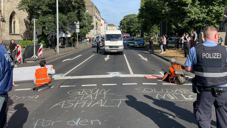 Klima-Protest in Koblenz: Mit einer Sitzblockade und festgeklebten Händen haben die Klima-Aktivisten am Freitagmorgen auf dem Friedrich-Ebert-Ring den Verkehr aufgehalten, er wurde schließlich umgeleitet. (Foto: SWR)