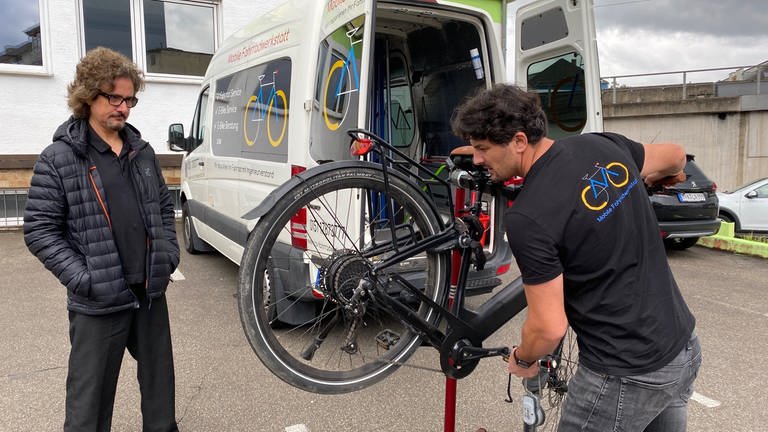 Nico untersucht bei einem Termin mit seiner mobilen Fahrradwerkstatt das E-Bike eines Kunden. (Foto: SWR)