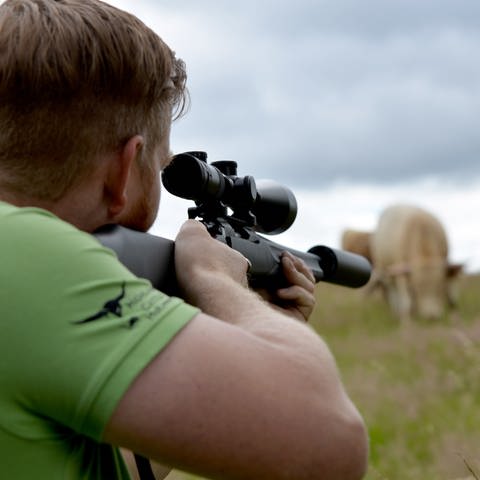 Rinderzüchter Christian Grommes deutet in einer gestellten Szene an, wie er mit dem "Weideschuss" ein Tier direkt auf der Weide tötet, um es später zu schlachten. 