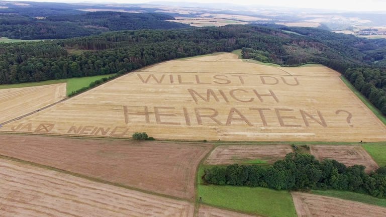 Landwirt macht Heiratsantrag und schreibt "Willst du mich heiraten" in Kornfeld