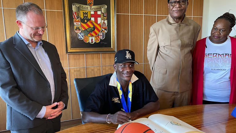 Basketball-Weltmeister Isaac Bonga trägt sich ins Goldene Buch der Stadt Neuwied ein.