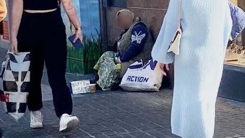 Bild zeigt eine Bettlerin, die vor einem Geschäft in Koblenz sitzt.