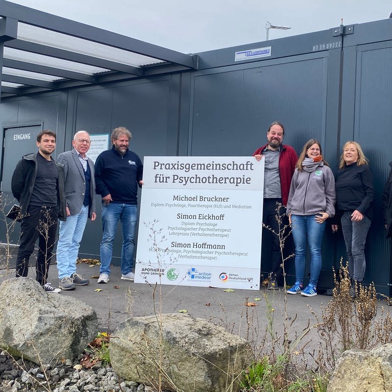 Die Psychologen stehen zusammen mit den Verantwortlichen von action medeor und Apotheker ohne Grenzen vor dem Container in Kalenborn.