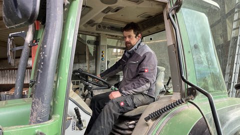 Biobauer René Bonn sitzt in seinem grünen Traktor am Steuer