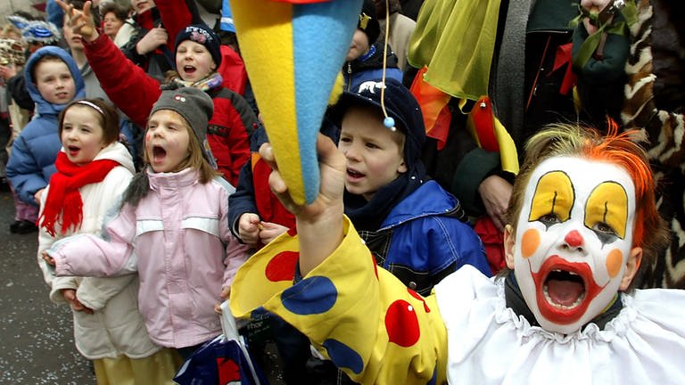 Lauthals "Kamelle" rufend, stehen Kinder am Straßenrand beim Karnevalsumzug.