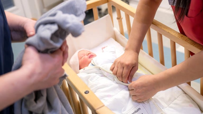 Ein Säugling liegt in einem Bett im Krankenhaus - die Geburtshilfestation Hachenburg wird einen Monat früher als geplant geschlossen. 