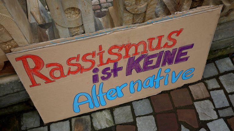 Pappschild mit der Aufschrift "Rassismus ist keine Alternative" (Foto: IMAGO, MŸller-Stauffenberg (Symbolbild))