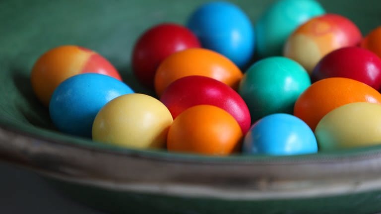 Frisch gefärbte Eier liegen in einer Schale: Hundertausende werden davon vor Ostern auf einem Geflügelhof in Mendig gekocht und gefärbt.