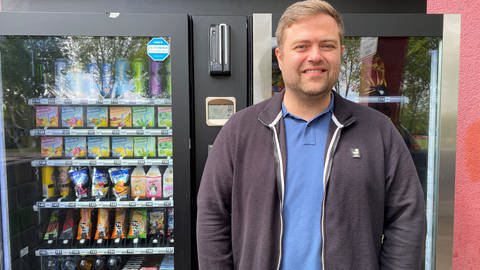 Betreiber Florian Bales steht vor dem Automatenkiosk mit Süßigkeiten. 