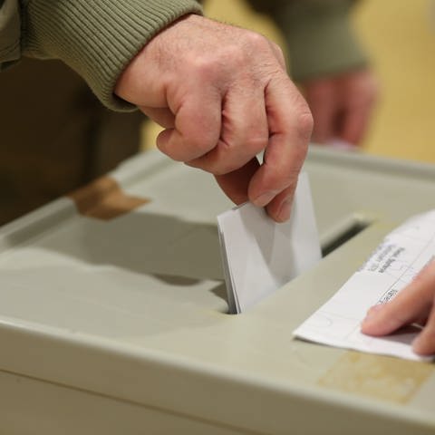 Ein Wahlberechtigter steckt seinen Stimmzettel in die Wahlurne in einem Wahlbüro. Symbolfoto