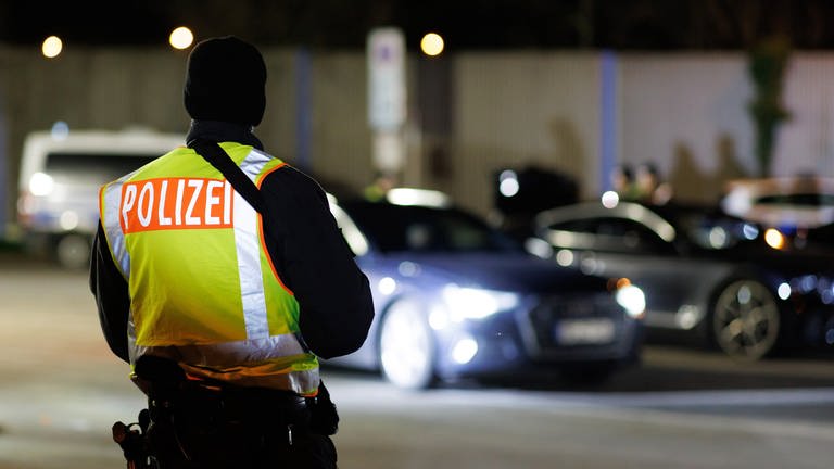 Ein Polizist steht am Rande einer Großkontrolle. In Koblenz wird nach einer verdächtigen Person gefahndet, die drei Menschen mit einer Stichwaffe angegriffen hat.