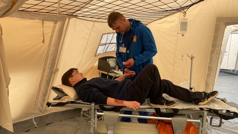 Ein freiwilliger Helfer verbindet bei der Notfall-Übung in Rech einem Statisten den Arm