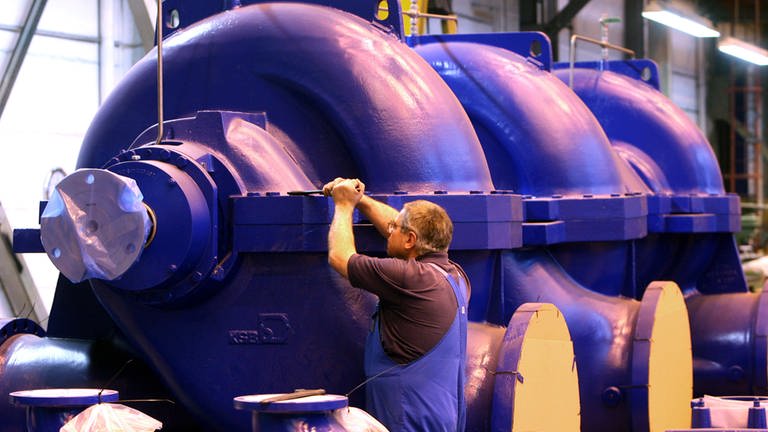 An überdimensionalen Wasserpumpen prüft ein Mitarbeiter die Schraubverbindungen.  (Foto: dpa Bildfunk, picture-alliance/ dpa | Peter Endig)