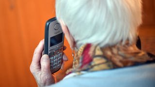 Seniorin hält ein Telefon (Foto: dpa Bildfunk, Picture Alliance)