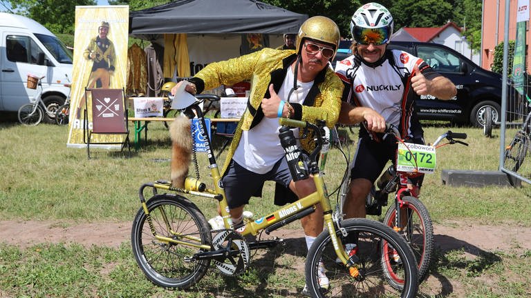 Radfahrer in goldener Kleidung neben Radfahrer mit Helmvisier vor den Augen (Foto: Pfälzer Klappverein / Ute Herzog)