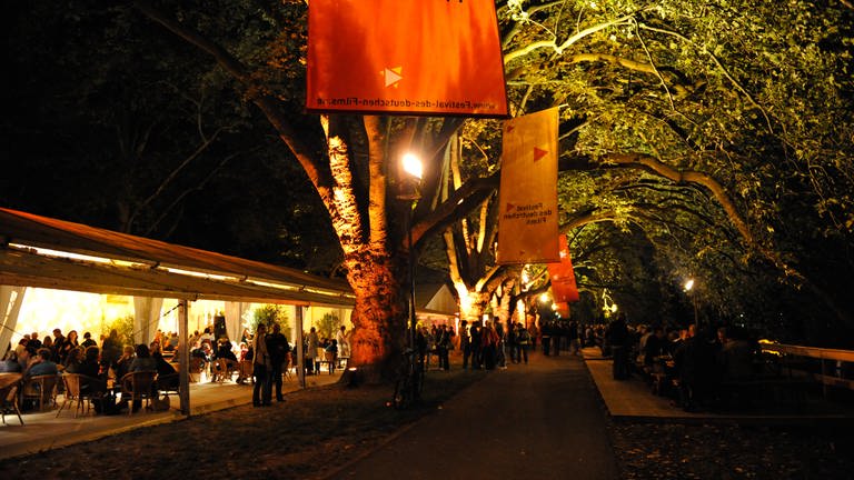 Filmfestival-Gelände am Abend mit Zelten und Bänken unter den Platanen auf der Parkinsel (Foto: SWR)