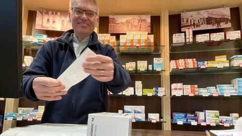 Apotheker Markus Wollny aus Ludwigshafen hält einen Kassenzettel in die Kamera in seiner Apotheke (Foto: SWR)