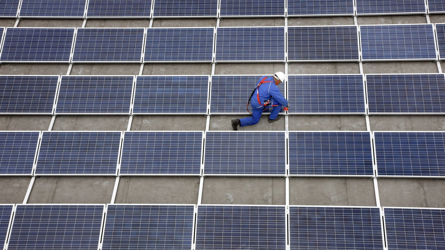 Monteur auf Solarfläche auf Flachdach. Symbolbild für Ludwigshafen investiert 7,5 Millionen Euro in Klima-Projekte (Foto: IMAGO, Jochen Tack)
