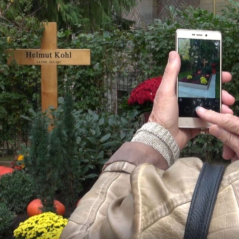Eine Frau fotografiert das Grab von Helmut Kohl in Speyer