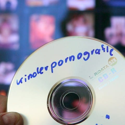 Ein Fahnder des Landeskriminalamtes hält eine CD mit kinderpornografischem Material in der Hand. (Foto: dpa Bildfunk, picture alliance / dpa | Peter Förster)