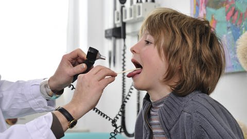 Arzt schaut krankem Kind in den Rachen (Foto: IMAGO, argum)