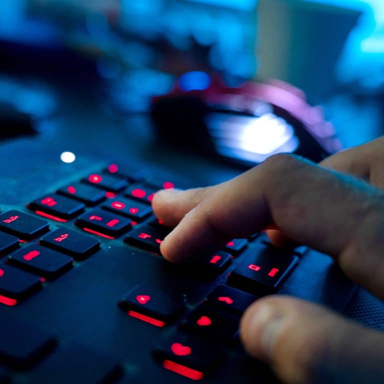 Ein Mann sitzt am Rechner und tippt auf einer Tastatur.