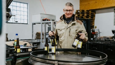 Ansgar Galler hällt mit Wein gefüllte Bierflaschen in die Kamera (Foto: Weingut Galler)
