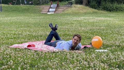Mann liegt auf Blumenwiese (Foto: Merlin Uhl)