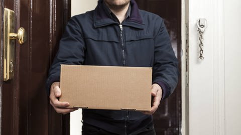 Paketbote in Wörth wird von Empfänger attackiert - Symbolbild Mann nimmt Paket an Haustür in Empfang (Foto: IMAGO, STPP)