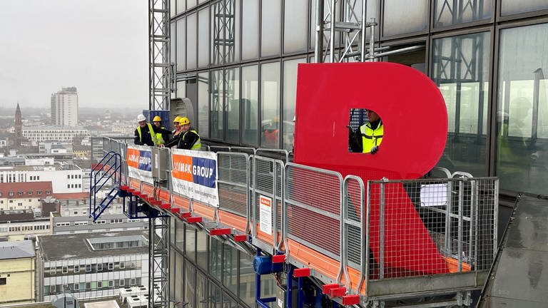 Arbeiter montieren den Buchstaben "R" des Schriftzuges des Rathaus Centers in Ludwigshafen ab. (Foto: SWR)