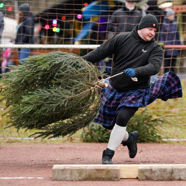 Da fliegt die Tanne: Ein Teilnehmer der inoffiziellen "Weltmeisterschaft" im Weihnachtsbaumwerfen.  (Foto: dpa Bildfunk, Picture Alliance)