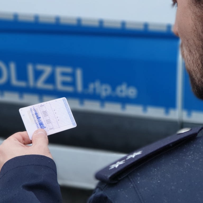Polizist kontrolliert einen Führerschein - Symbolbild zur Meldung falsche Lkw-Fahrerin bei Dannstadt-Schauernheim erwischt (Foto: Polizei)