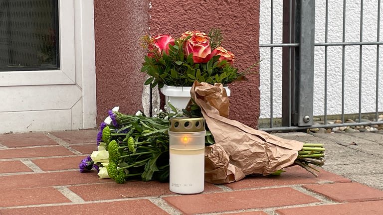 Blumen und eine Kerze vor einer Kita in Limburgerhof erinnern an das tote Kind (Foto: SWR)