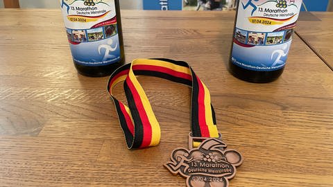 Zwei Weinflaschen liegen auf einem Tisch, sowie eine Medaille  (Foto: SWR)