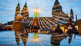 Der Dom und die festliche Beleuchtung auf dem Mainzer Weihnachtsmarkt spiegeln sich in einer glänzenden Oberfläche. (Foto: dpa Bildfunk, picture alliance/dpa | Frank Rumpenhorst)