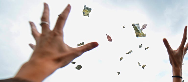 Ausgestreckte Hände versuchen flatternde Geldscheine aus der Luft zu fangen. (Foto: dpa Bildfunk, picture alliance / dpa | Andreas Arnold)