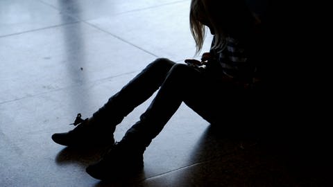 Ein kleines Mädchen sitzt mit gesenktem Kopf allein auf dem Fußboden. Wegen Corona haben viele Kinder psychische Probleme. (Foto: dpa Bildfunk, picture alliance/dpa/dpa-Zentralbild | Britta Pedersen)
