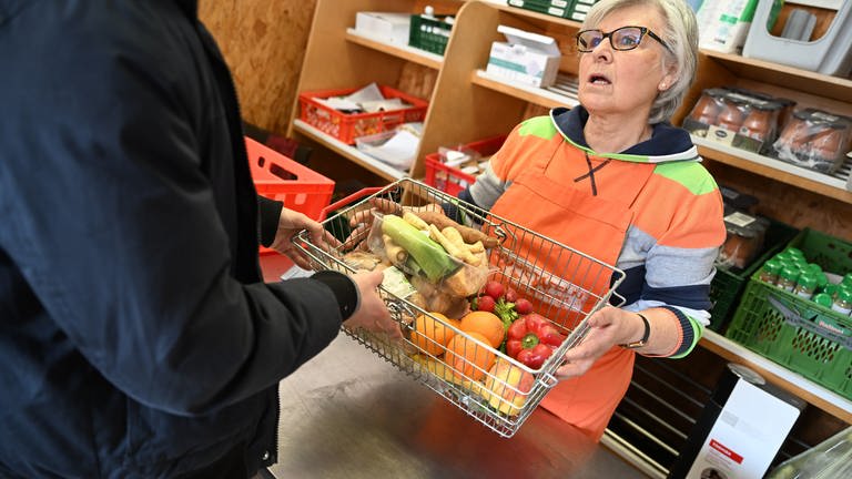 Eine ehrenamtliche Helferin einer Tafel gibt Lebensmittel an einen Bedürftigen ab. (Foto: dpa Bildfunk, Picture Alliance)