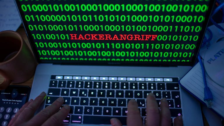 Zwischen dem Binärcode auf einem Laptopmonitor ist das Wort Hackerangriff zu sehen.  (Foto: dpa Bildfunk,  Jens Büttner)
