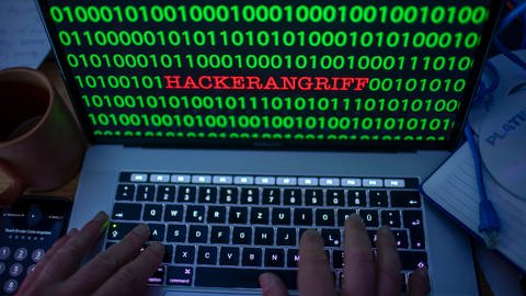 Zwischen dem Binärcode auf einem Laptopmonitor ist das Wort Hackerangriff zu sehen.  (Foto: dpa Bildfunk,  Jens Büttner)