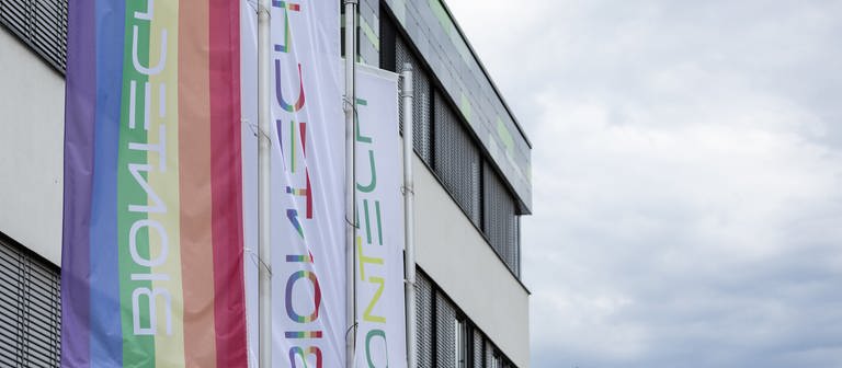 Vor der Zentrale von BioNTech an der Mainzer Goldgrube wehen Fahnen, darunter eine Regenbogenfahne (Foto: dpa Bildfunk, Picture Alliance)