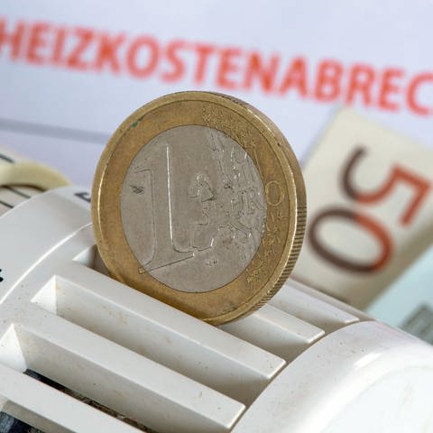 Eine Ein-Euro-Münze vor einem Stapel mit Heizkostenabrechnungen (Foto: picture-alliance / Reportdienste, picture alliance / dpa | Jens Büttner)