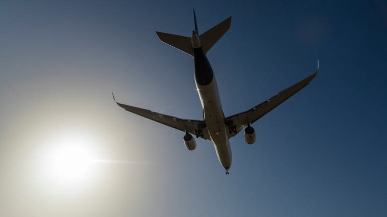 Ein Flugzeug von unten am blauen Himmel, an dem die Sonne scheint (Foto: dpa Bildfunk, Picture Alliance)