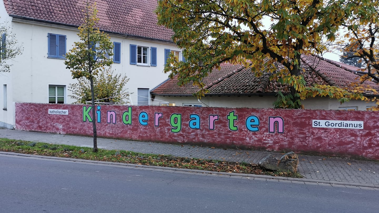 katholischer Kindergarten steht auf der Mauer vor dem Kitagelände