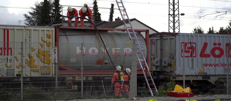 Spezialkräfte pumpen die Salzsäure aus dem undichten Kesselwagen am Bahnhof Gau-Algesheim. (Foto: SWR)