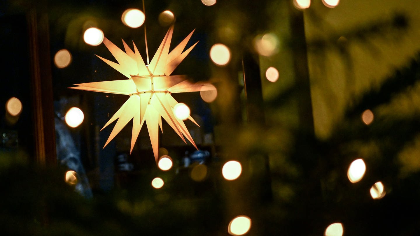 Ein leuchtender Weihnachtsstern hängt an einem Ladengeschäft. (Foto: dpa Bildfunk, picture alliance/dpa/dpa-Zentralbild | Britta Pedersen)