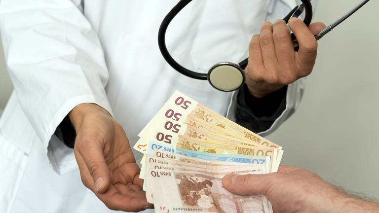 Ein Arzt hält die Hand auf und bekommt mehrere Euro Scheine gereicht. (Foto: picture-alliance / Reportdienste, Picture Alliance)