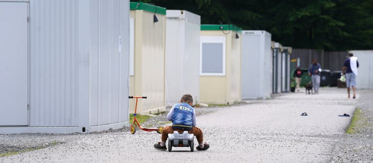 Eine Junge fährt auf einem Bobbycar vor den Wohn-Containern seiner Flüchtlingsutnerkunft. (Symbol)  (Foto: dpa Bildfunk, picture alliance/dpa | Marcus Brandt)